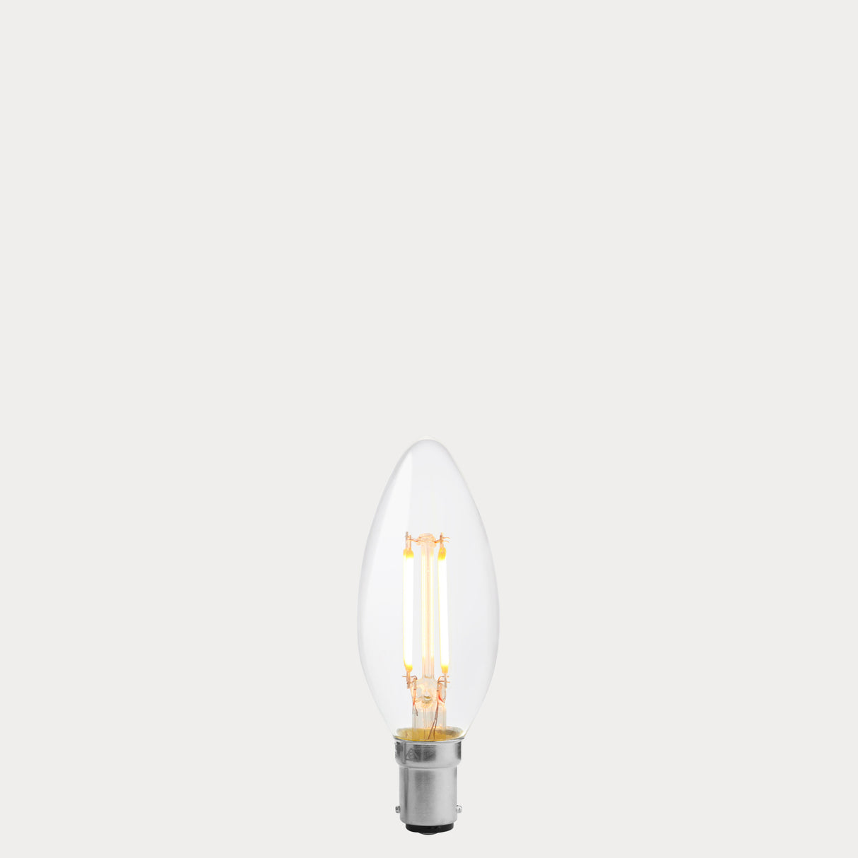 Dulora 4W B15 LED candle bulb in clear glass, glowing with 2200K extra warm white light.