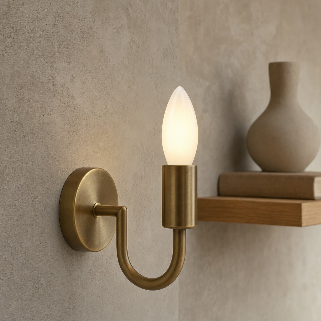 Luxury Wall Mounted Dulora Frosted Dimmable Candle LED Bulb in 2700K Warm White illuminated inside a modern brushed brass U-shaped wall sconce.