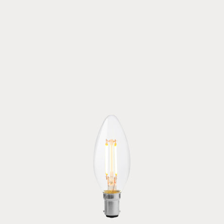 Dulora 4W B15 LED candle bulb in clear glass, glowing with 2200K extra warm white light.
