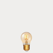 Dulora 4W Vintage Fancy Round LED Bulb E27 in Ultra Warm White glowing with deep amber warmth through tinted glass