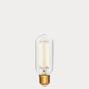 Dulora 6.5W E27 LED tubular filament bulb in clear glass, glowing with 2200K extra warm white light.