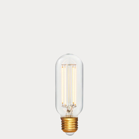 Dulora 6.5W E27 LED tubular filament bulb in clear glass, glowing with 2200K extra warm white light.